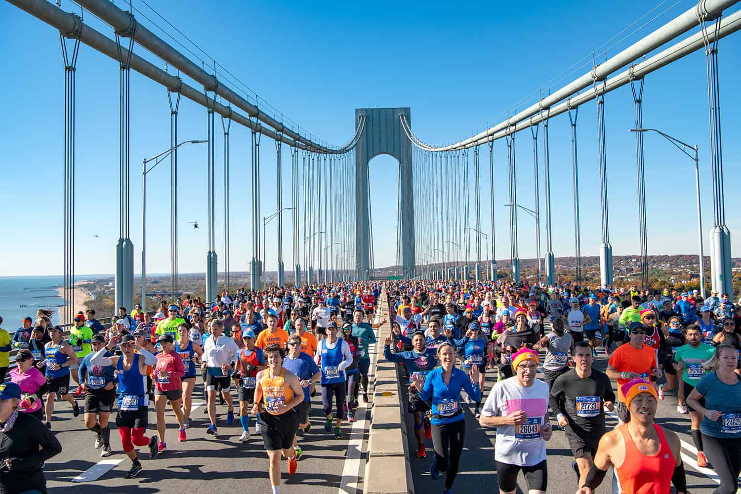 Coureurs traversant le Verrazano-Narrows Bridge lors du NYC Half Marathon avec une vue spectaculaire sur le pont suspendu emblématique de New York.