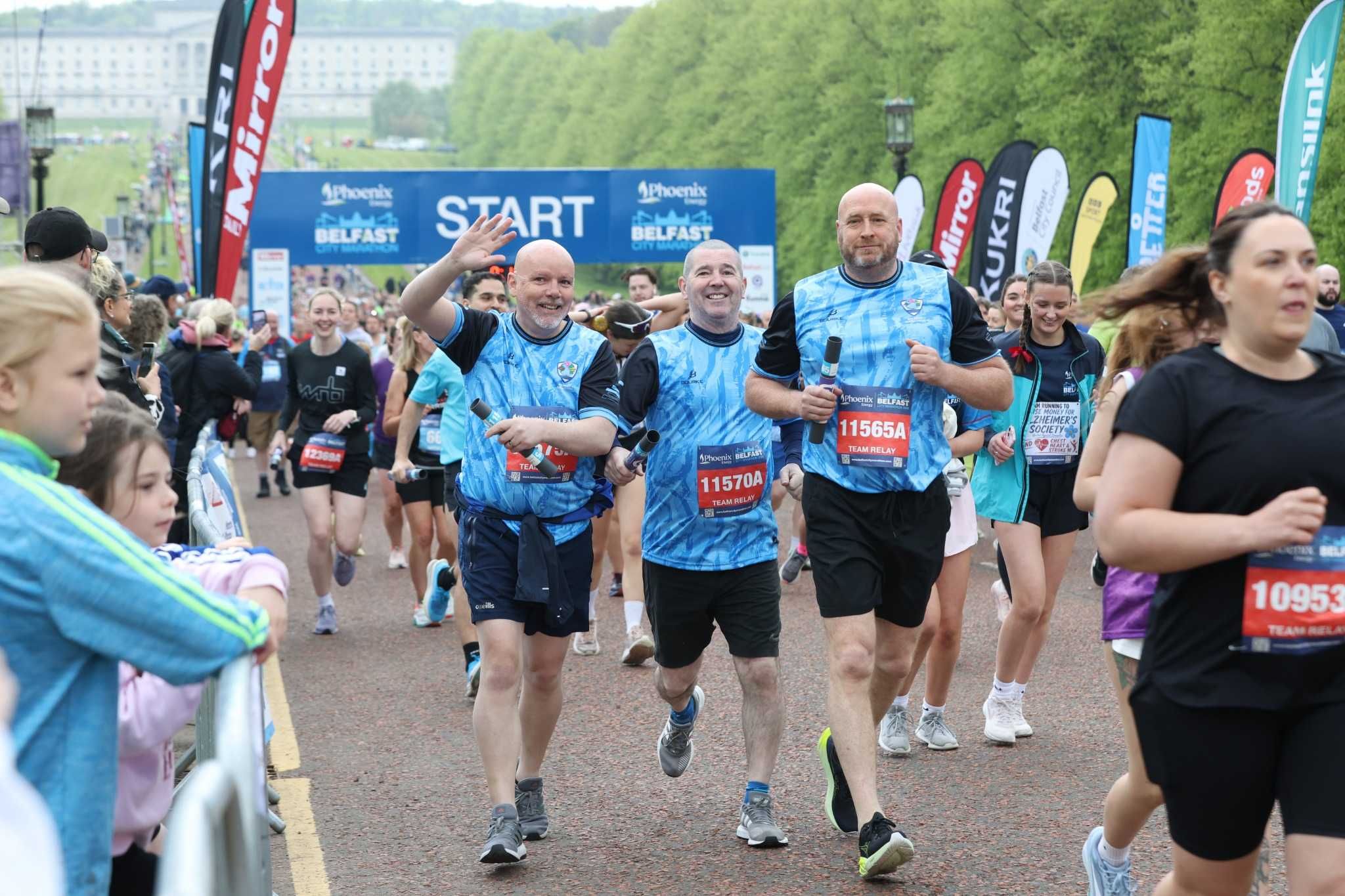 Participants souriants du Phoenix Energy Belfast City Half Marathon franchissant la ligne de départ devant le Parlement de Stormont.