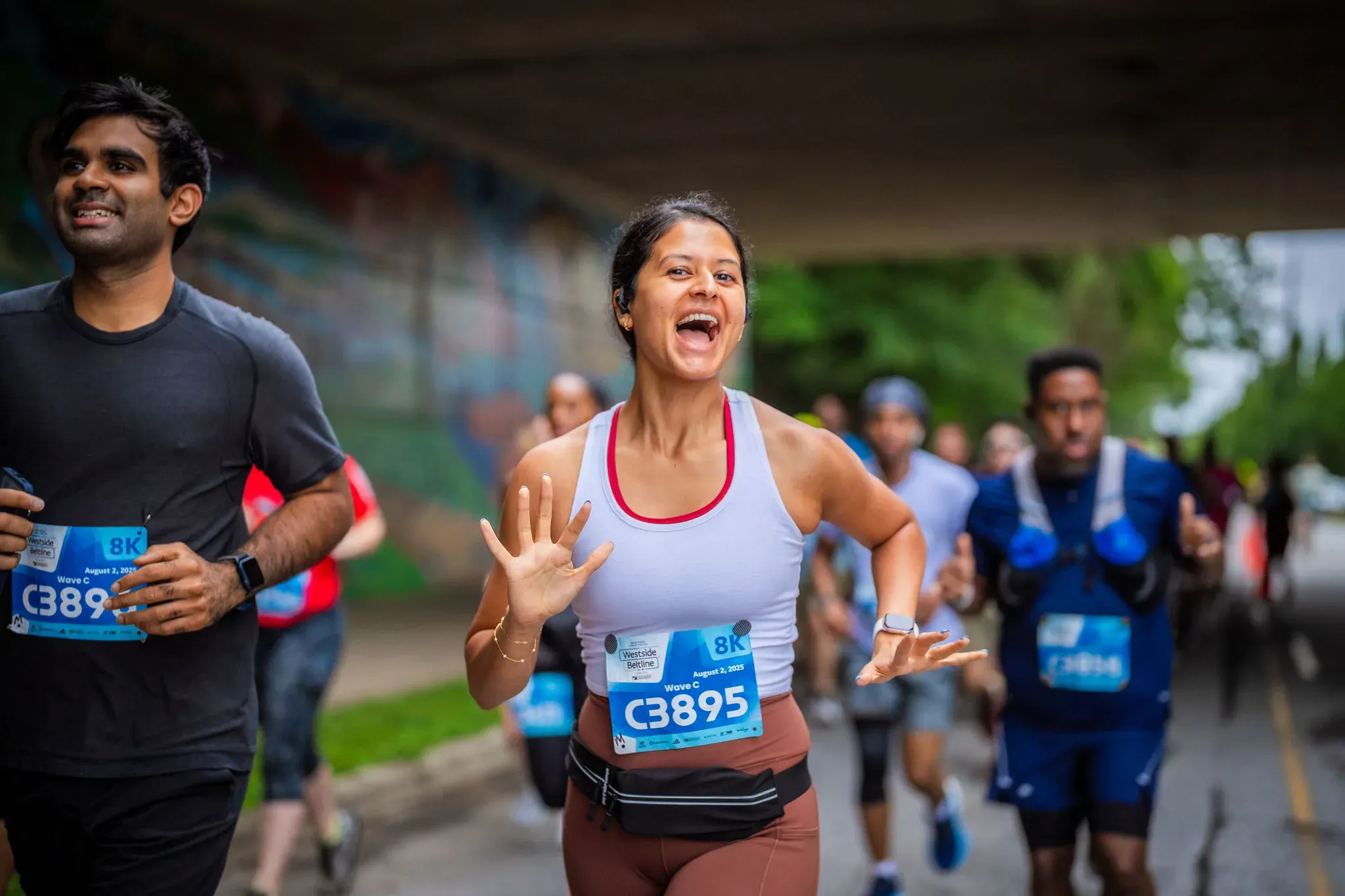 Des coureurs en pleine action sur le parcours du 8K Southside BeltLine, affichant sourires et détermination.