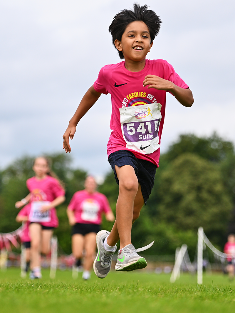 Jeune coureur en pleine action lors de la course, arborant un sourire radieux.