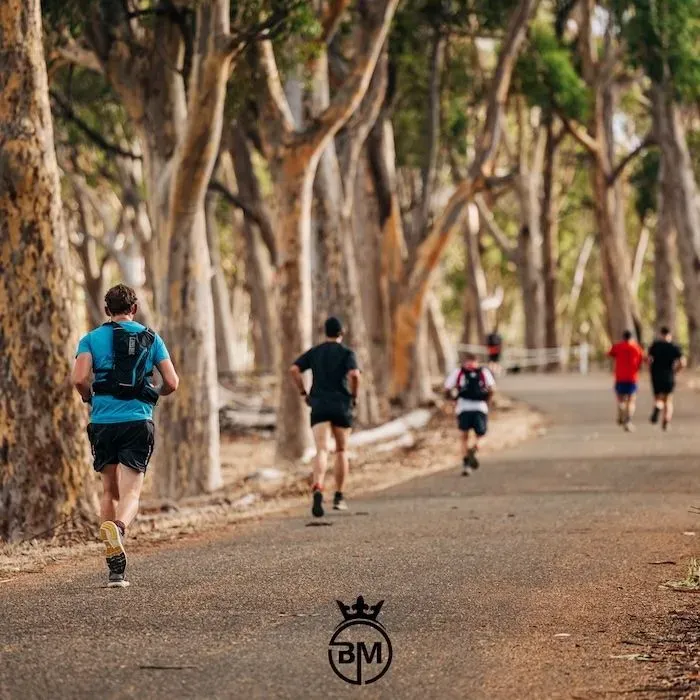Groupe de coureurs sur un chemin bordé d'eucalyptus typiques de la région australienne du Yurrebilla Trail.