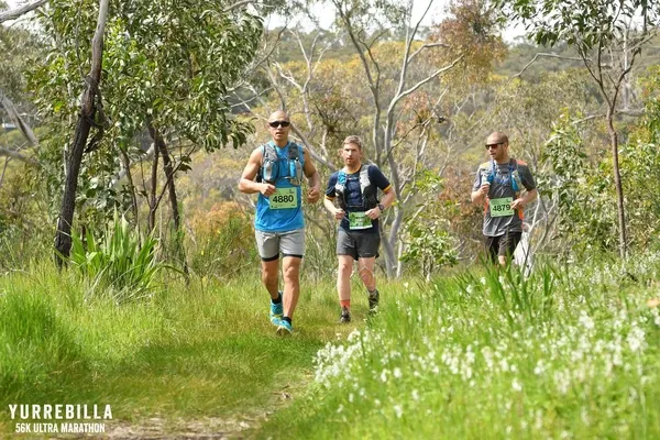 Trois coureurs évoluant sur un sentier verdoyant entouré de végétation australienne pendant le Yurrebilla Ultra Marathon.