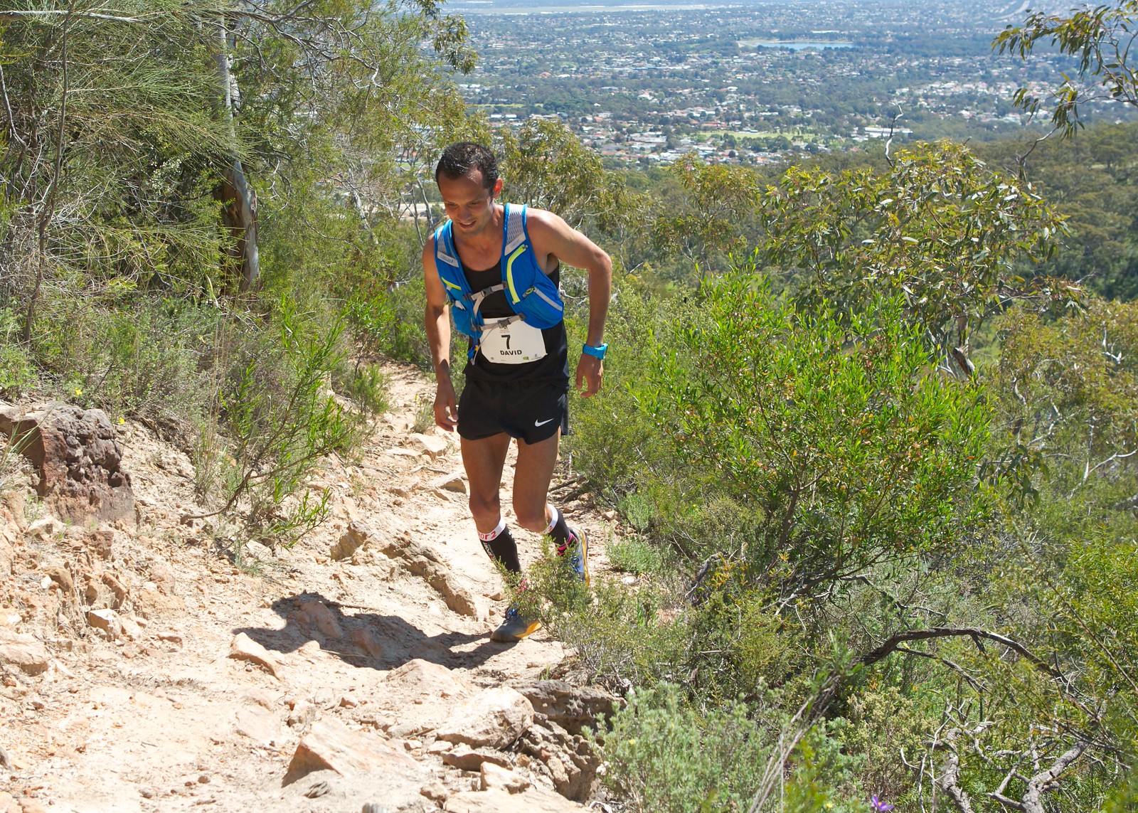 Coureuse en action sur un sentier rocailleux avec vue panoramique sur la ville d'Adélaïde en arrière-plan lors du Yurrebilla Ultra Marathon.