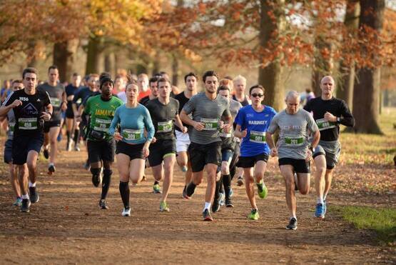 Peloton de coureurs traversant Richmond Park en automne, avec les feuillages colorés en arrière-plan.