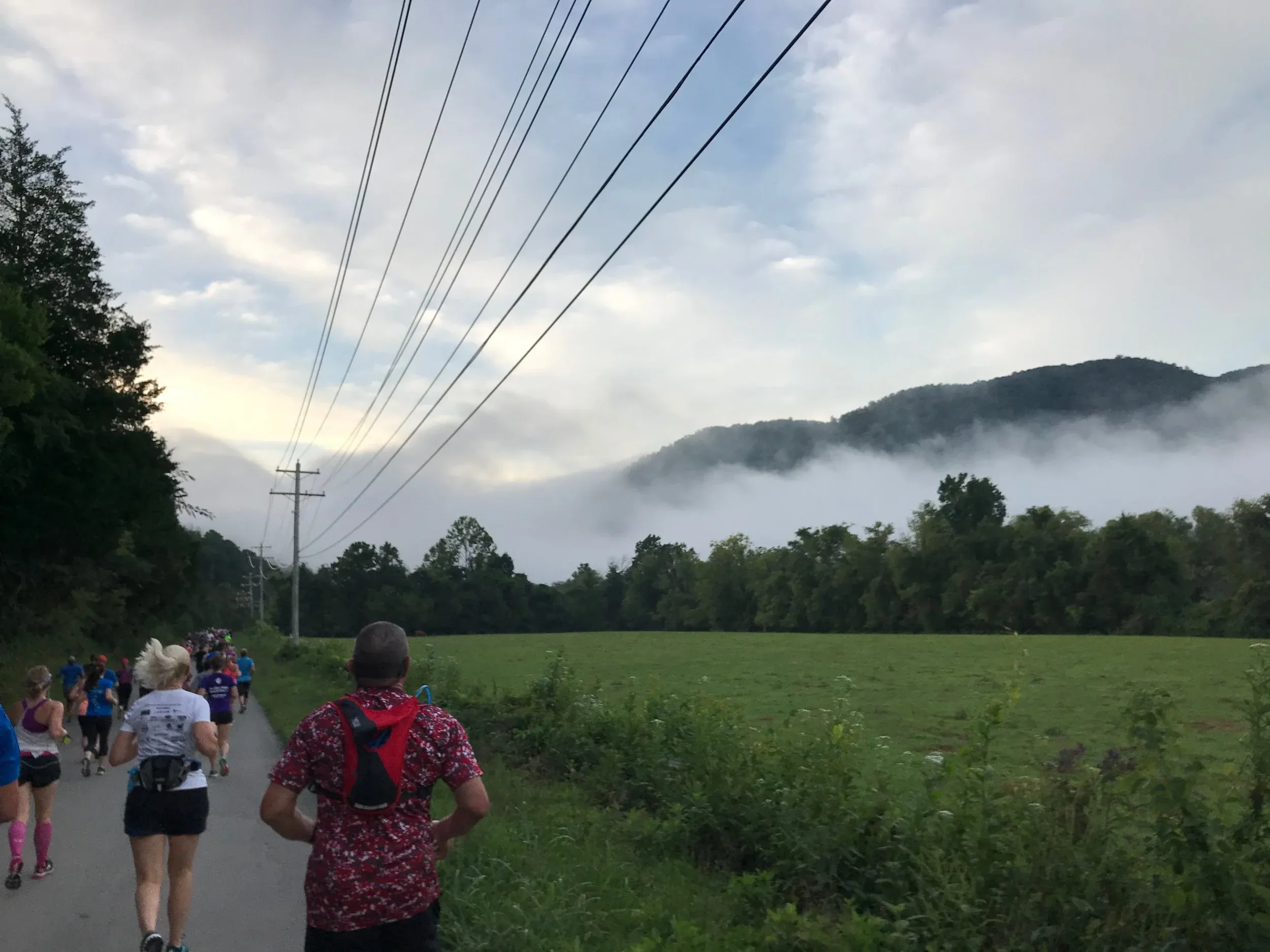 Coureurs au petit matin avec la brume matinale enveloppant les montagnes en arrière-plan, créant une atmosphère magique.