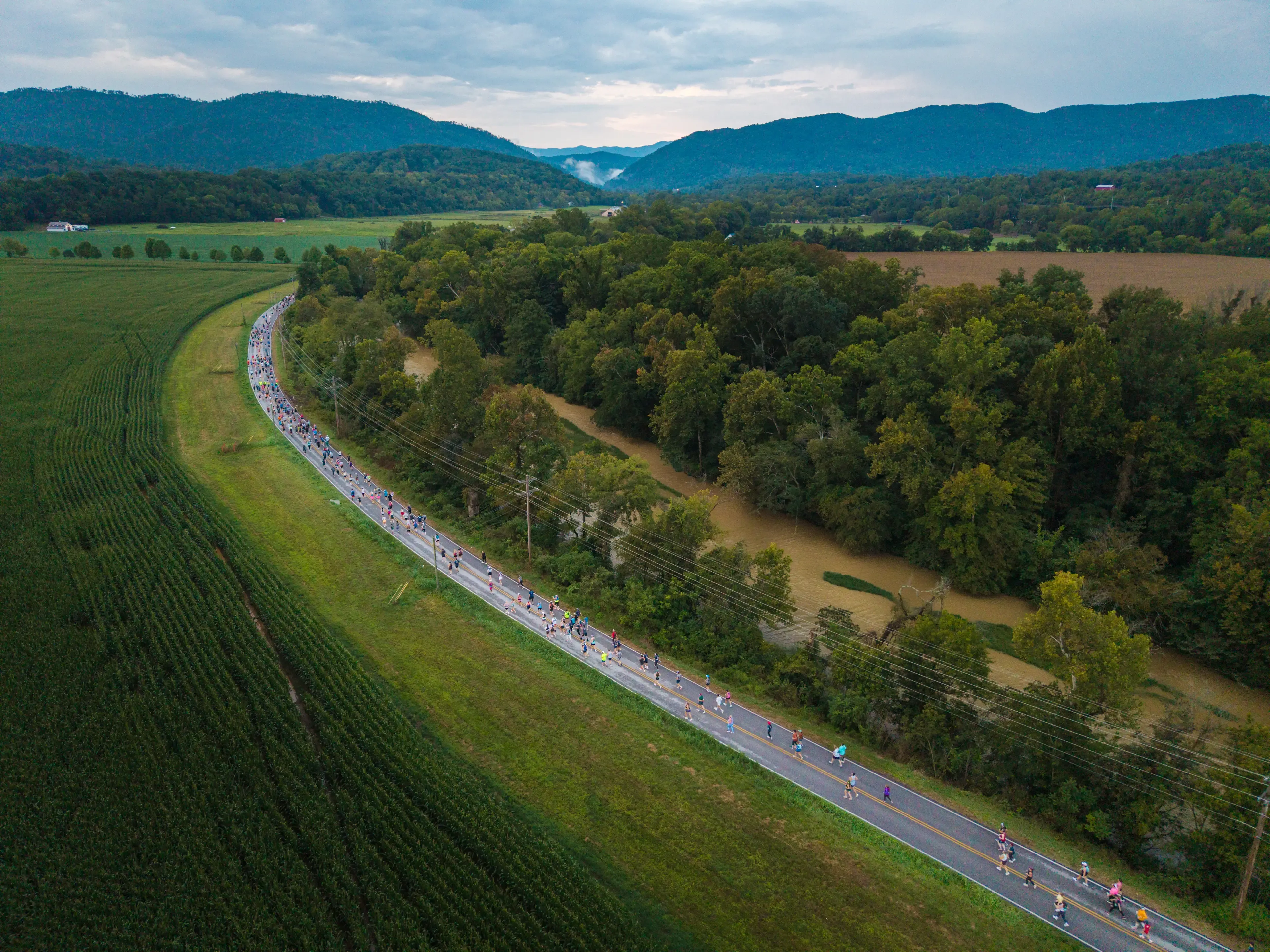 Vue aérienne spectaculaire du peloton de coureurs serpentant sur la route au cœur des vallées verdoyantes des Great Smoky Mountains.